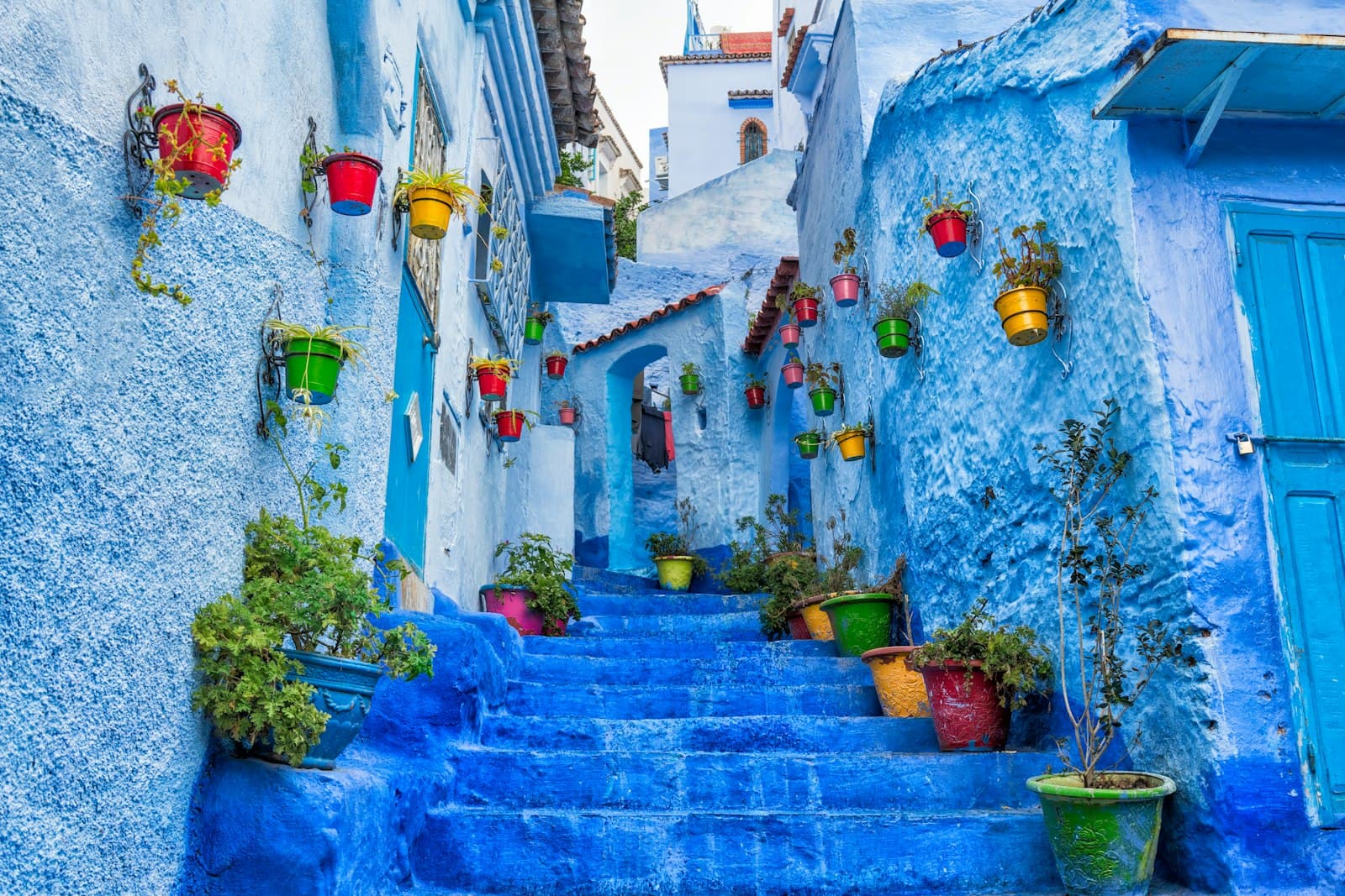 Chefchaouen — a narrow street with blue steps and potted plants